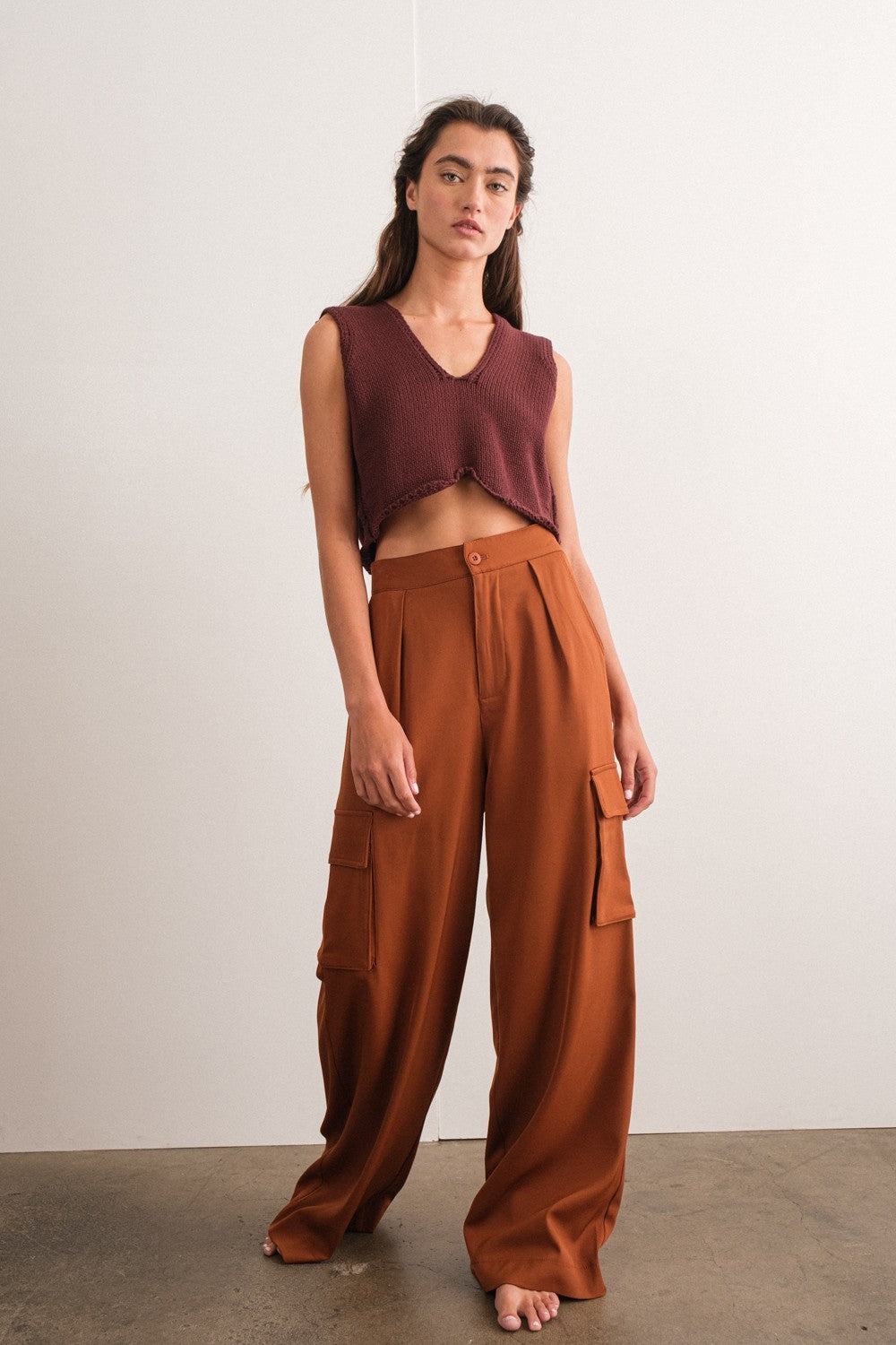 woman wearing a burgundy cropped sleeveless top and high-waisted brown cargo pants with side pockets