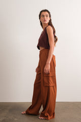 woman wearing a maroon cropped top and wide-leg rust orange pants, standing against a plain background