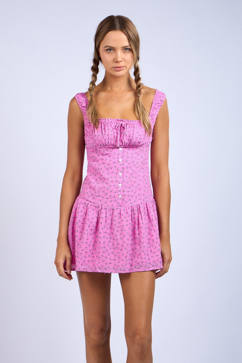 woman wearing a pink floral short dress with a fitted bodice and tiered ruffle hem
