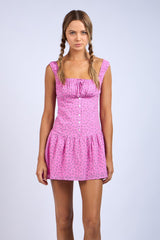woman wearing a pink floral short dress with a fitted bodice and tiered ruffle hem