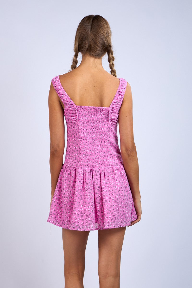 woman wearing a pink summer dress with a flared skirt and ruffled straps, viewed from the back