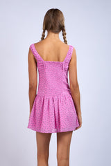 woman wearing a pink summer dress with a flared skirt and ruffled straps, viewed from the back