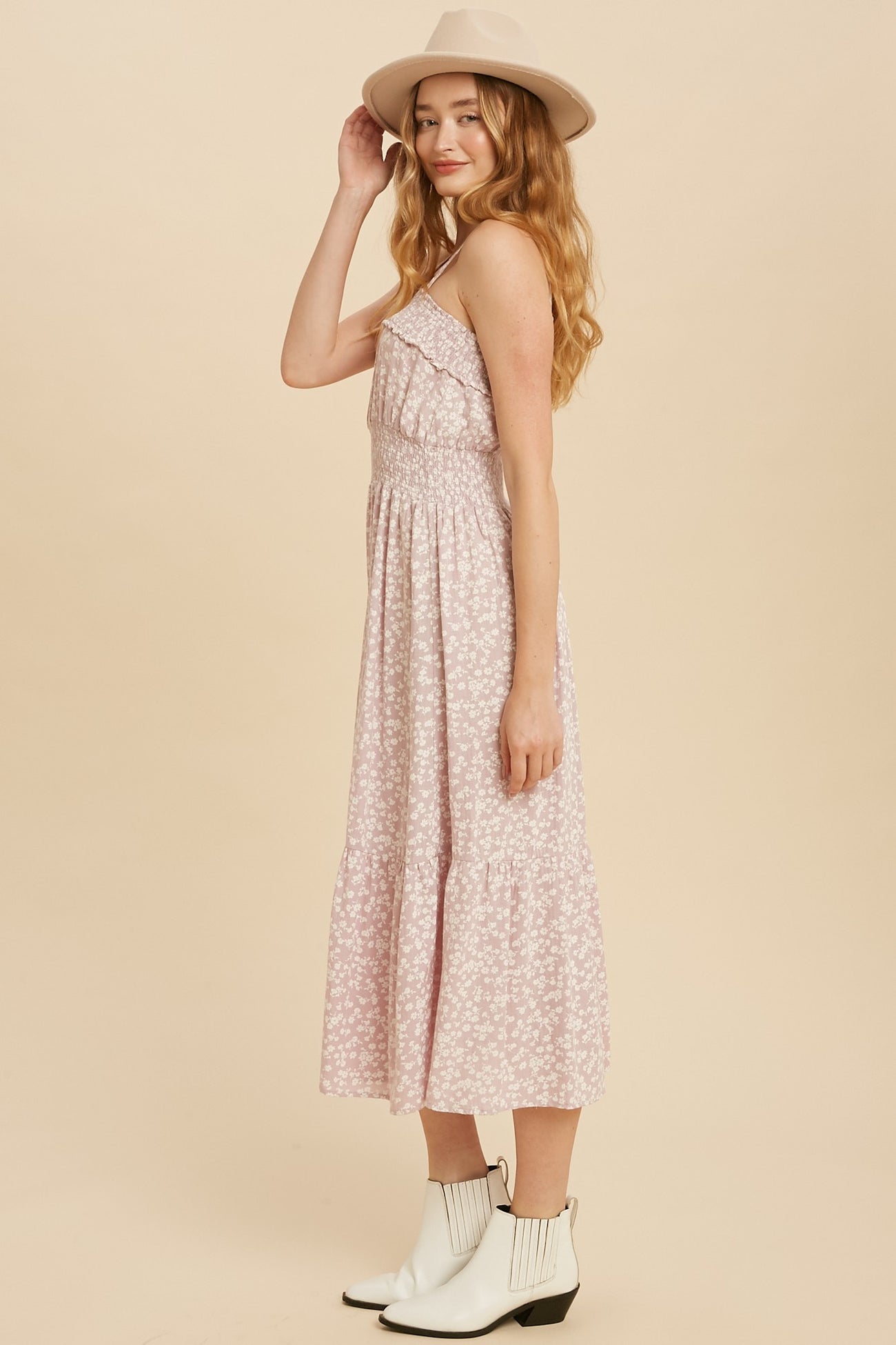 woman wearing a pink floral maxi dress with ruffle detailing and a fitted bodice, paired with a wide-brimmed hat and ankle booties