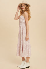 woman wearing a pink floral maxi dress with ruffle detailing and a fitted bodice, paired with a wide-brimmed hat and ankle booties