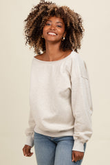 woman wearing a light beige off-the-shoulder sweatshirt with long sleeves and blue jeans