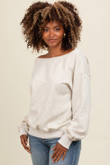 woman wearing a light beige off-the-shoulder sweater with balloon sleeves and light blue fitted jeans