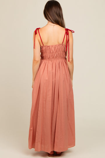 woman wearing a dusty rose maternity maxi dress with adjustable tie straps and smocked back detail