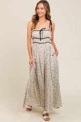 woman wearing a floral maxi dress with a sweetheart neckline, black detailing, and adjustable straps