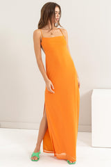 woman wearing an orange sleeveless maxi dress with a side slit and minimalist straps