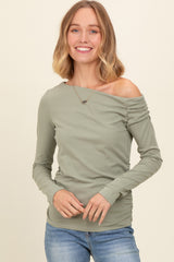 woman wearing a muted green off-shoulder long sleeve top with gathered detail and smiling