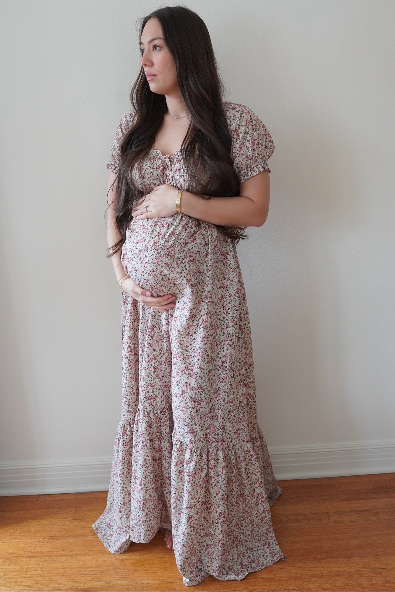 woman wearing a floral long sleeve maternity dress and holding her baby bump