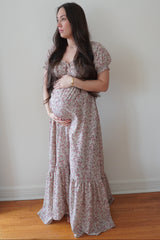 woman wearing a floral long sleeve maternity dress and holding her baby bump