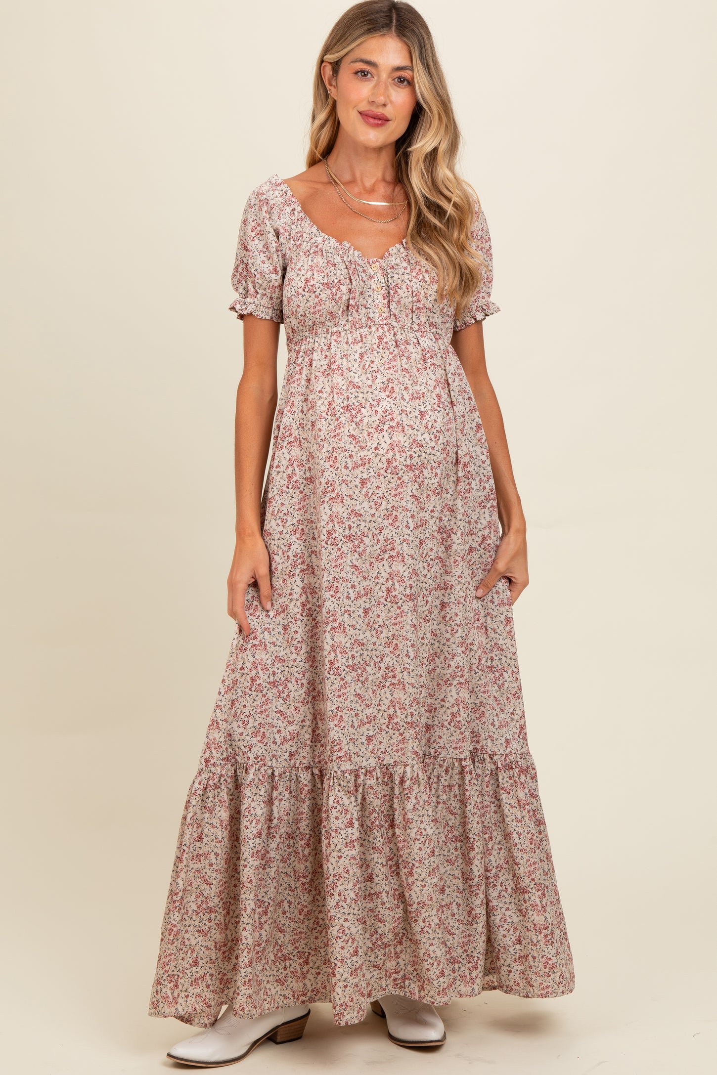 woman wearing a floral maternity maxi dress with short puff sleeves and a tiered hem, showcasing her baby bump