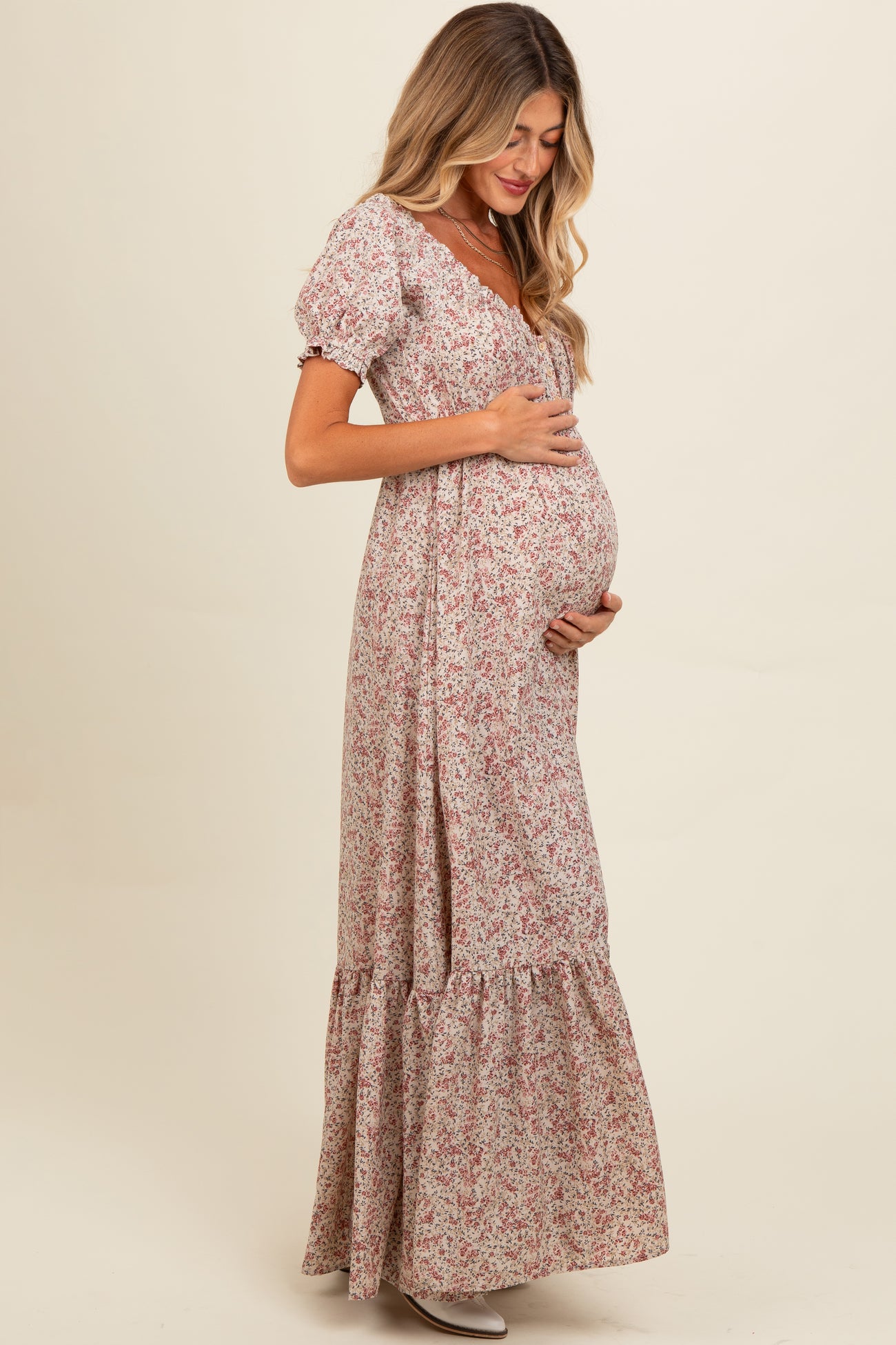 woman wearing a floral maternity maxi dress and holding her baby bump