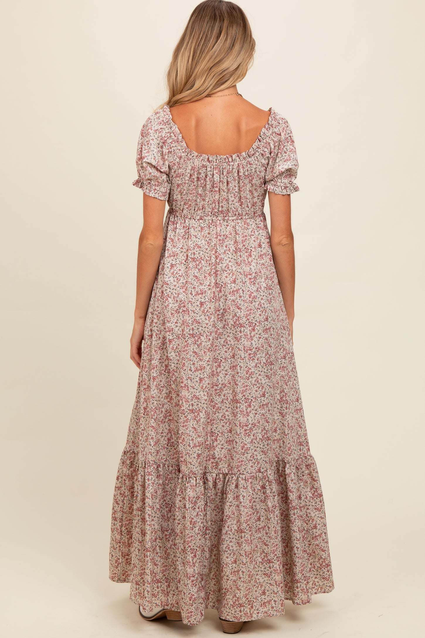 woman wearing a floral long maternity maxi dress with puff sleeves and a tiered hem, showing the back view