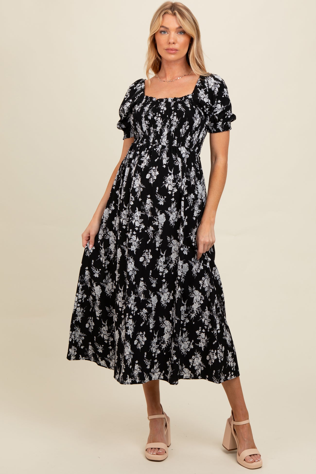 woman wearing a black floral maternity maxi dress with puff sleeves and a square neckline, featuring a baby bump