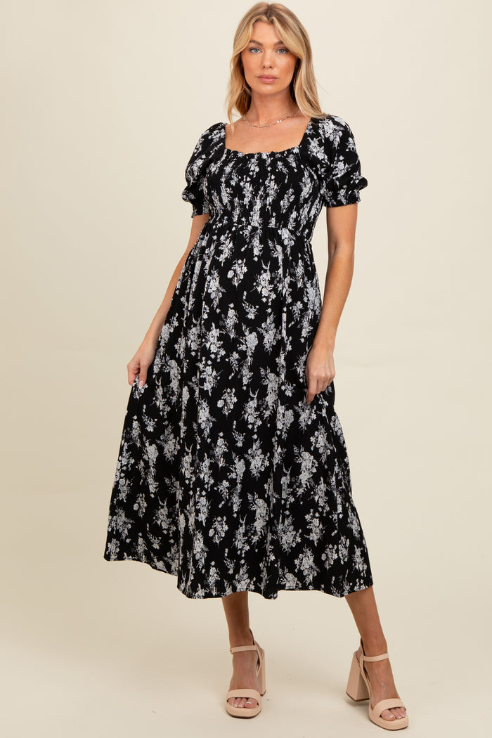 woman wearing a black floral maternity maxi dress with puff sleeves and a square neckline, featuring a baby bump