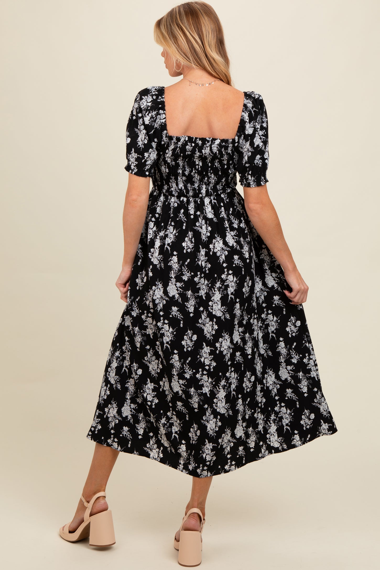 woman wearing a black floral print maternity maxi dress with puff sleeves and a square neckline
