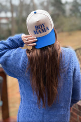 woman wearing a blue knitted sweater and a beige and blue cap that says "boy mama
