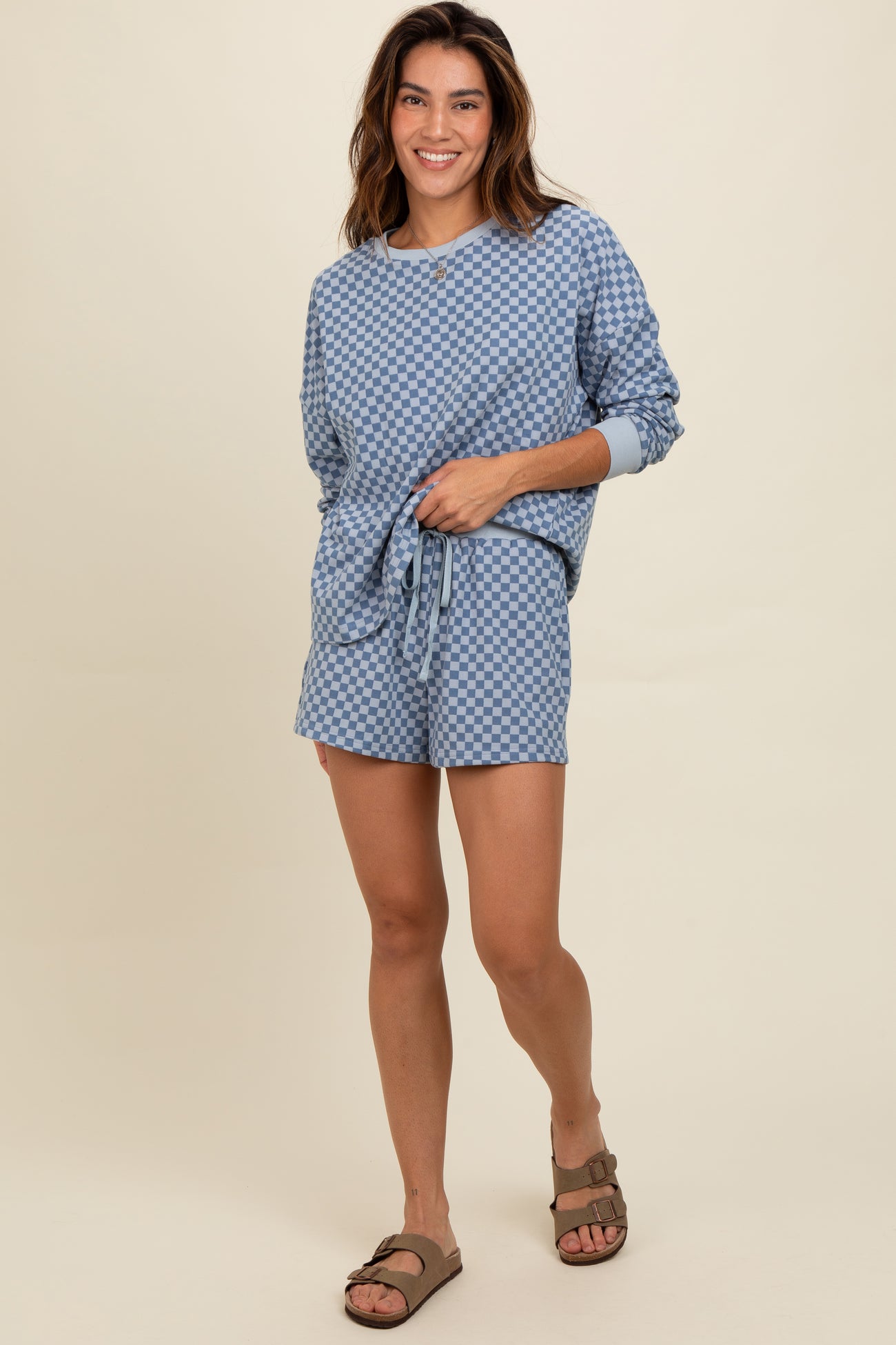 woman wearing a blue checked loungewear set with a loose long sleeve top and matching shorts