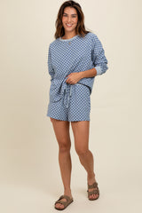woman wearing a blue checked loungewear set with a loose long sleeve top and matching shorts