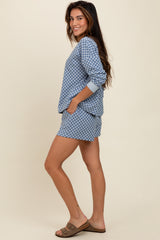 woman wearing a blue checked long sleeve top with pockets and matching shorts, styled casually.
