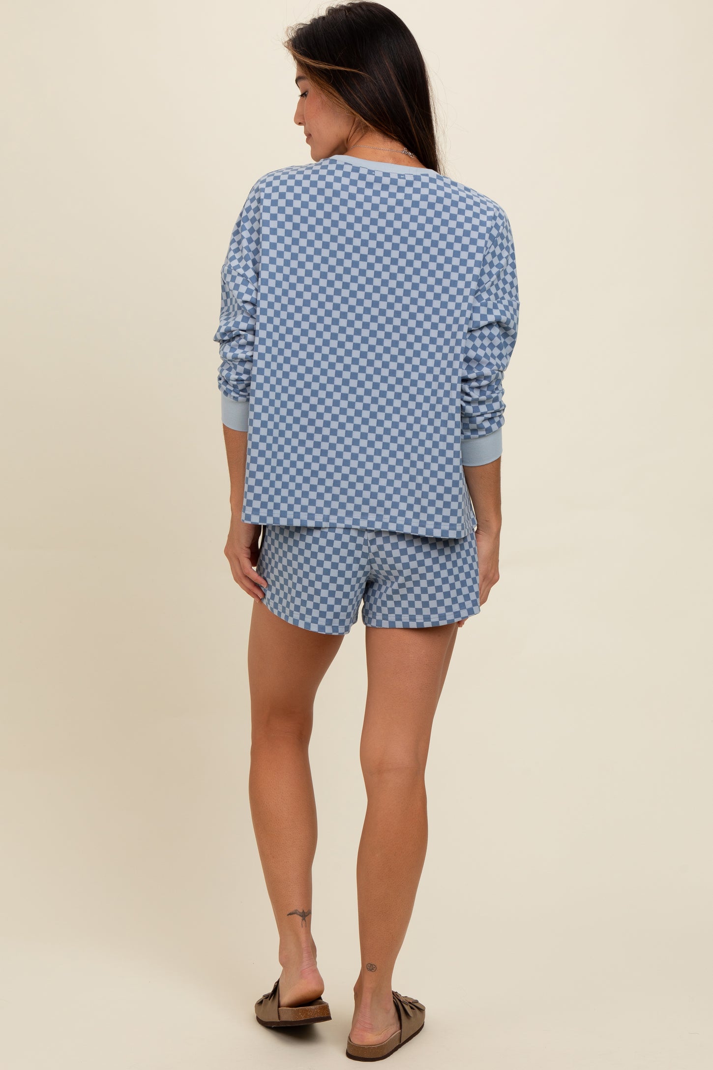 woman wearing a blue checkerboard long sleeve top with matching shorts, viewed from the back