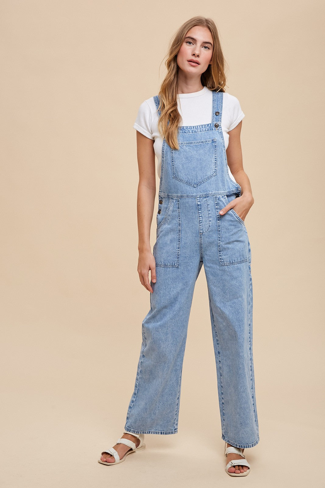 woman wearing a light blue denim overall with wide legs and a white t-shirt underneath