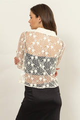 woman wearing a sheer lace blouse with a patterned back, styled over a black skirt