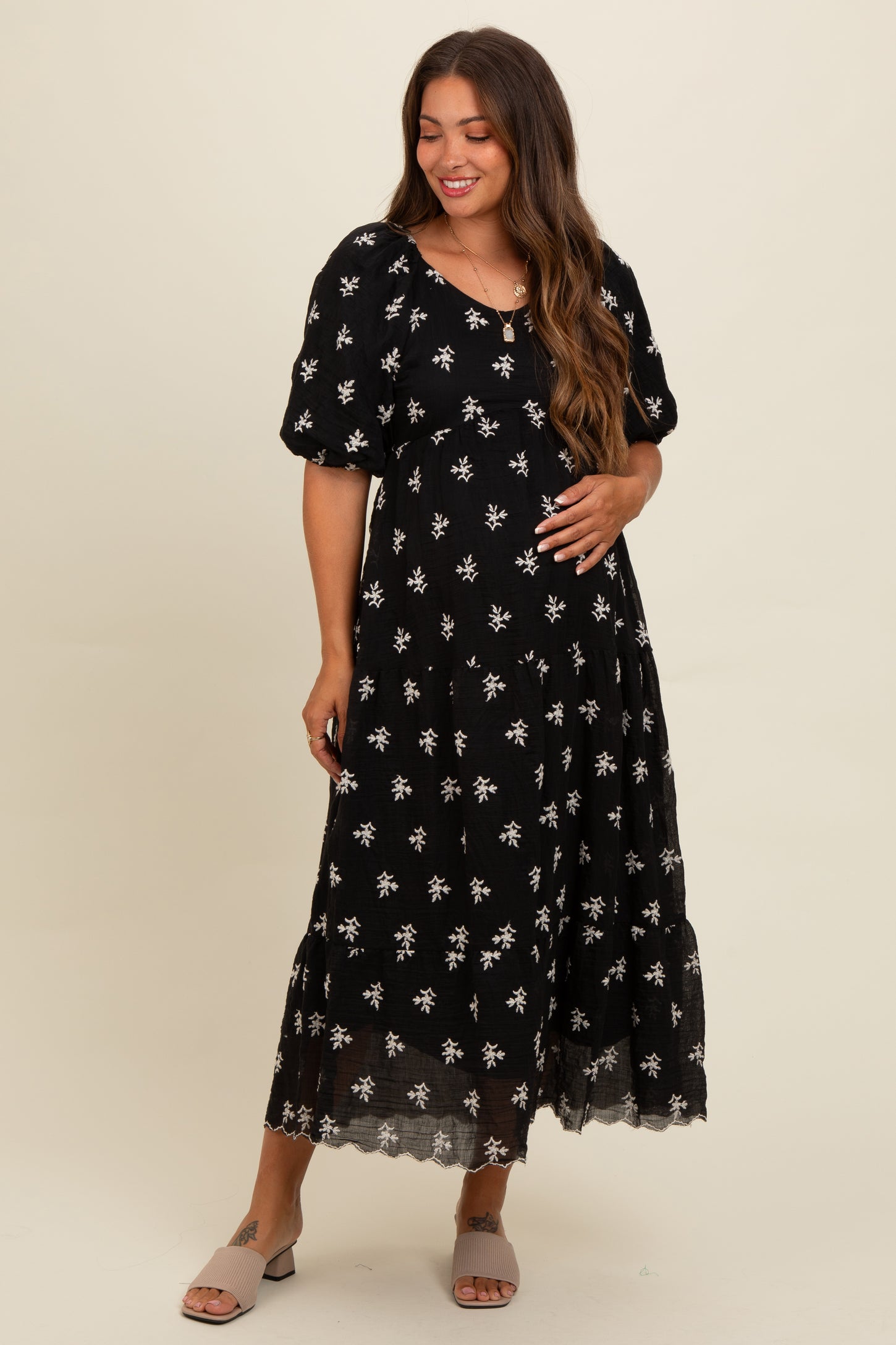 woman wearing a black floral maternity maxi dress and showing her baby bump