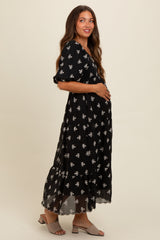 woman wearing a black floral maternity maxi dress and holding her baby bump