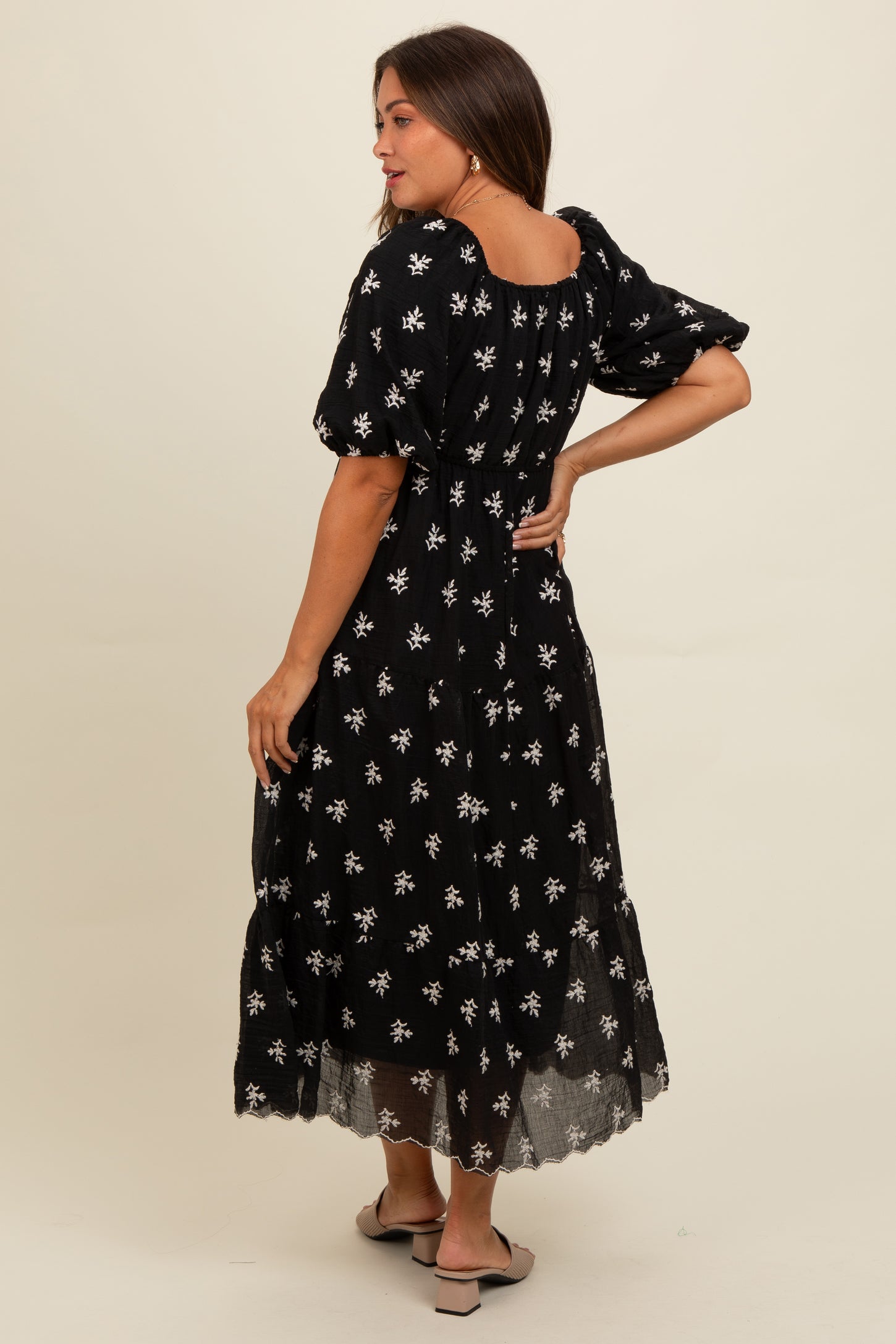 woman wearing a black floral maternity dress with puff sleeves and a tiered skirt