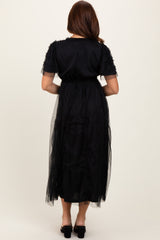 woman wearing a black maxi dress with ruffle details and a sheer overlay, shown from the back