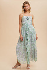 woman wearing a floral maxi dress with a ruffled detail and a rose accent, styled with strappy heels