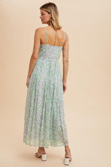woman wearing a light green floral maxi dress with a smocked back and thin straps