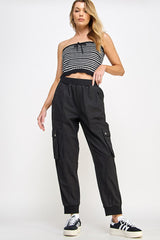 woman wearing a cropped black and white striped tank top and black cargo pants with pockets