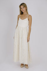 woman wearing a cream spaghetti strap maxi dress with floral embroidery and a ruched bodice