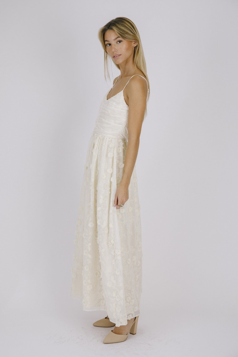 woman wearing a cream floral maxi dress with adjustable spaghetti straps and a flowing skirt