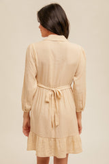 woman wearing a lightweight beige striped shirt dress with a cinched waist and ruffled hem, shown from the back