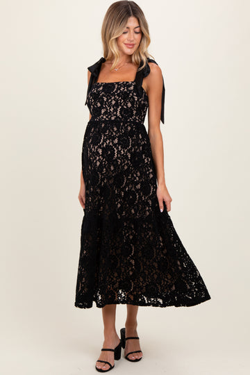 woman wearing a black lace maternity dress with tie straps and a visible baby bump