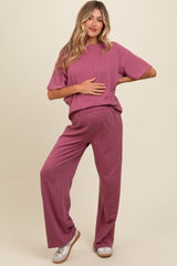 woman wearing a mauve ribbed maternity lounge set and holding her baby bump