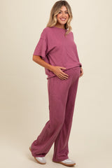 woman wearing a mauve ribbed maternity loungewear set with a relaxed fit and holding her baby bump