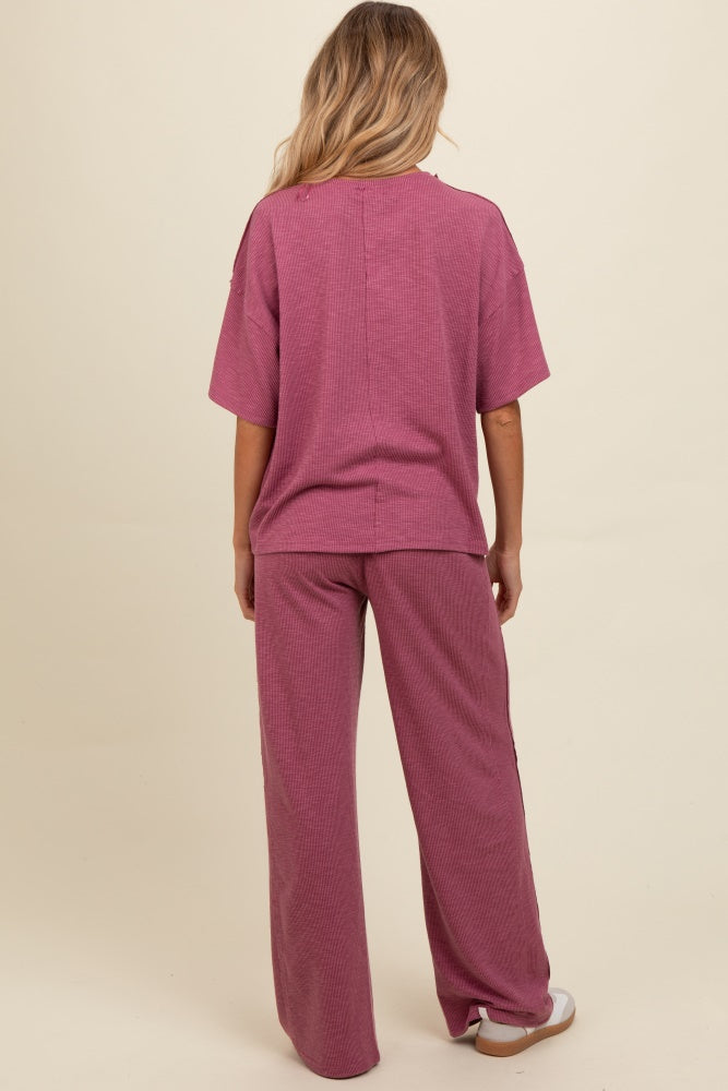 woman wearing a pink ribbed maternity loungewear set with oversized top and wide-leg pants, showing her baby bump
