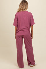 woman wearing a pink ribbed maternity loungewear set with oversized top and wide-leg pants, showing her baby bump