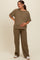 woman wearing a brown ribbed maternity top and matching pants, holding her baby bump