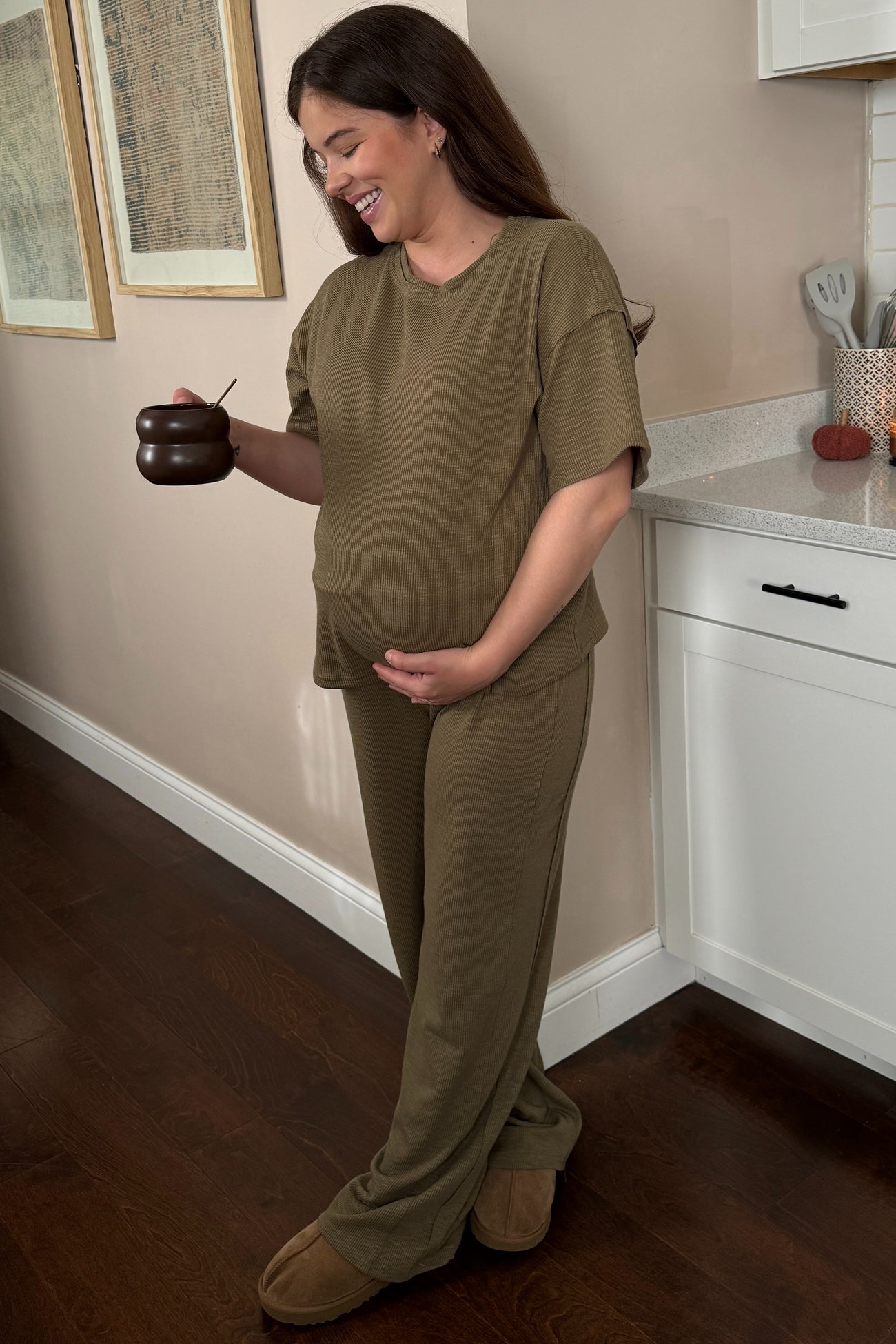 woman wearing an olive green ribbed maternity loungewear set and holding her baby bump