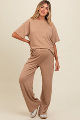 woman wearing a beige maternity lounge set with a short sleeve top and wide leg pants, showing a baby bump