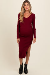 woman wearing a burgundy ribbed maternity dress with a deep v-neck and side slit, showcasing her baby bump