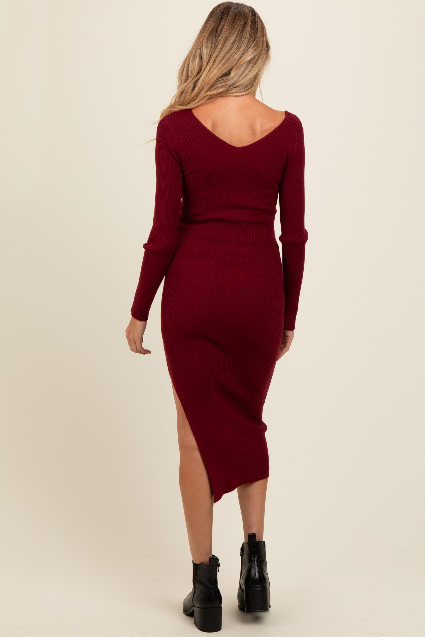 woman wearing a burgundy ribbed maternity dress with a V-back and side slit, showing a baby bump