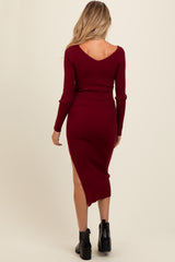 woman wearing a burgundy ribbed maternity dress with a V-back and side slit, showing a baby bump